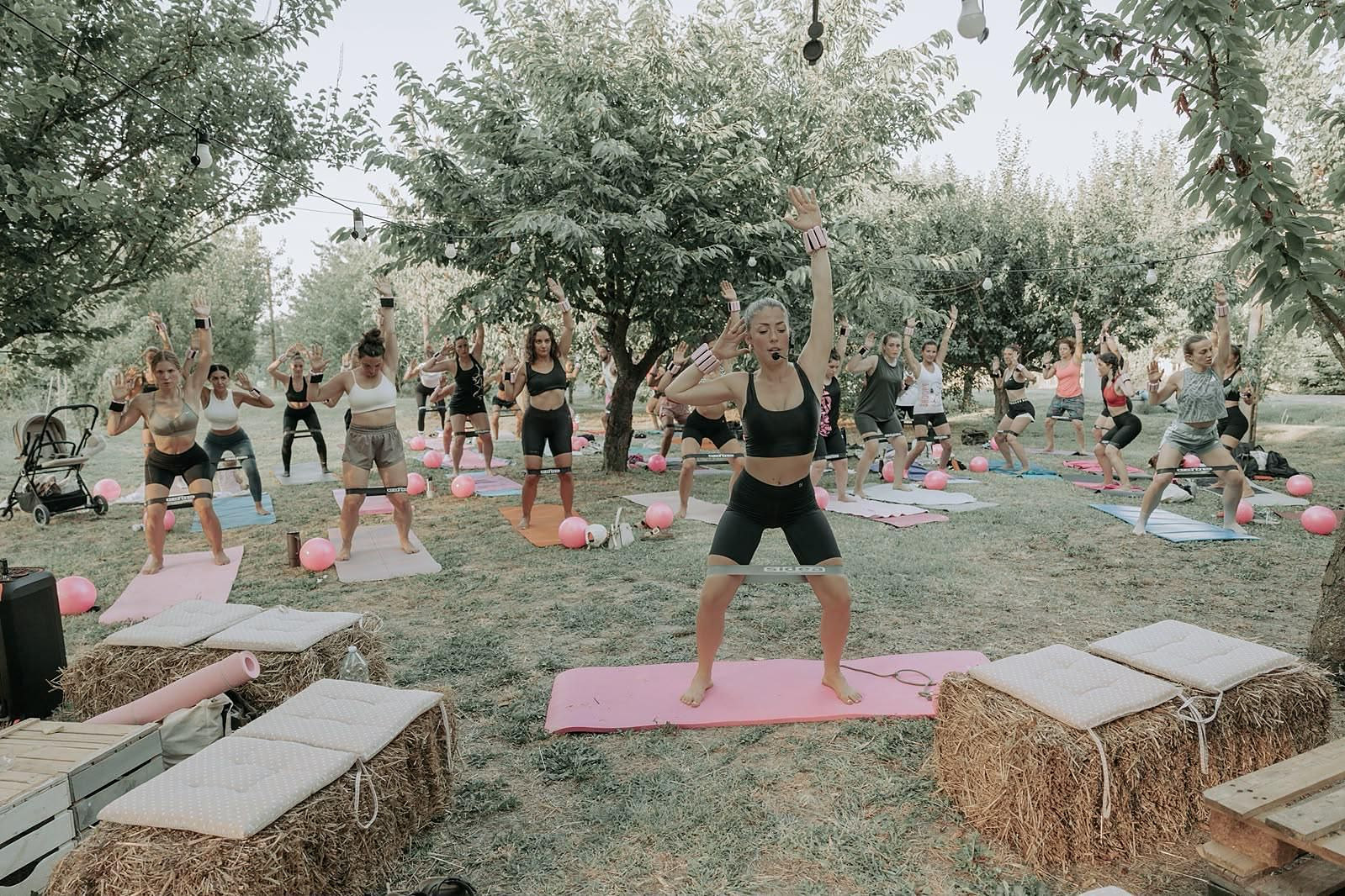 Laurona guida la lezione di pilates nel frutteto davanti a decine di partecipanti