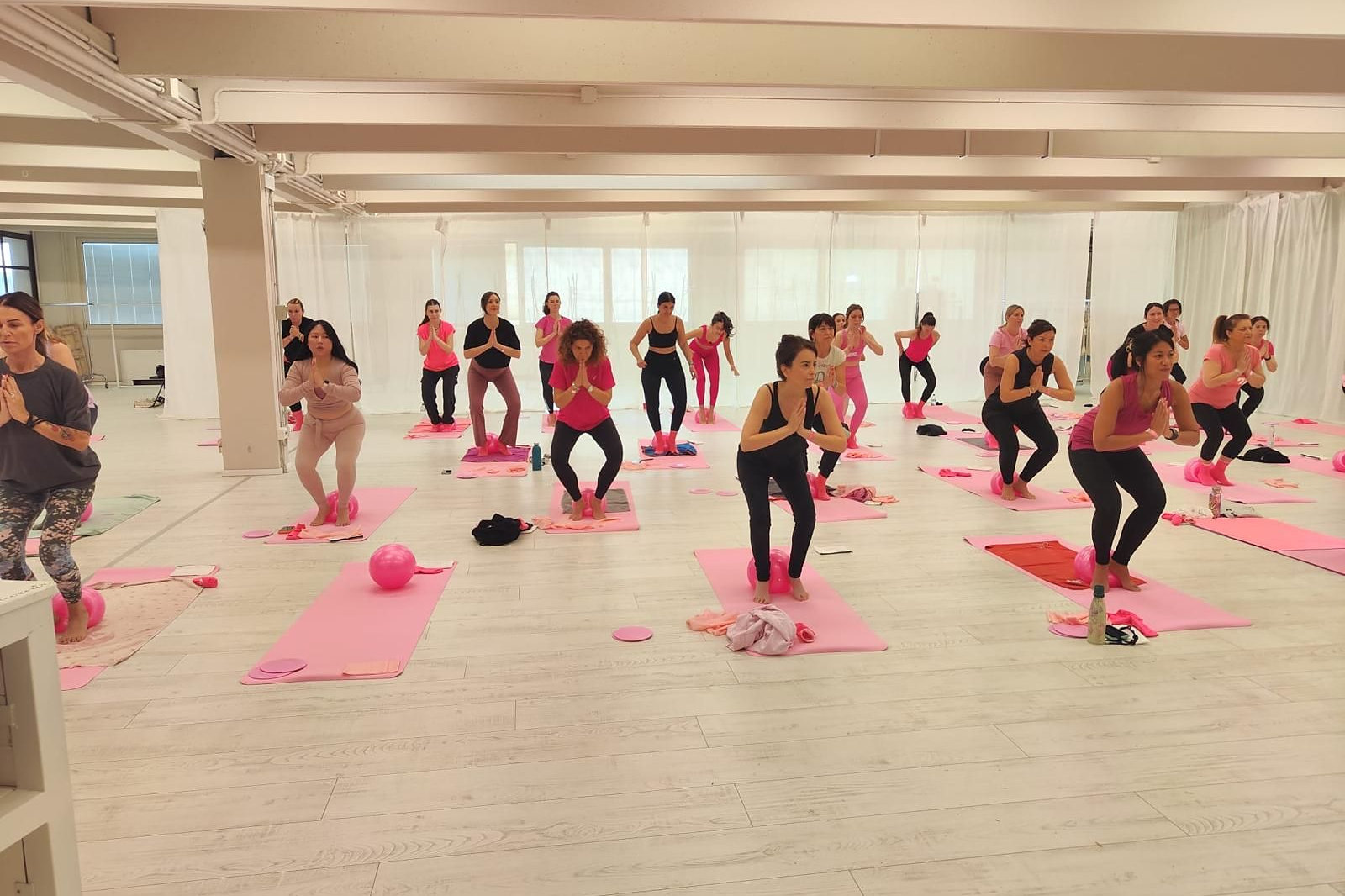 Le partecipanti alla masterclass in posizione di squat con le mani giunte